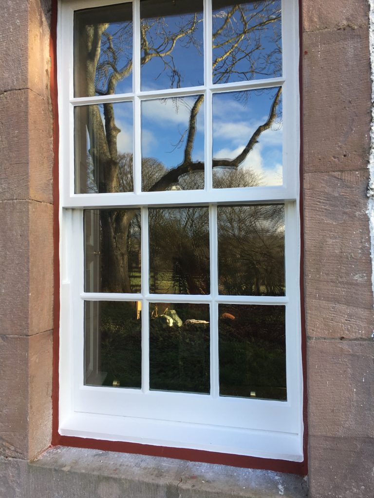 Restored white timber sash and case window in a stone property